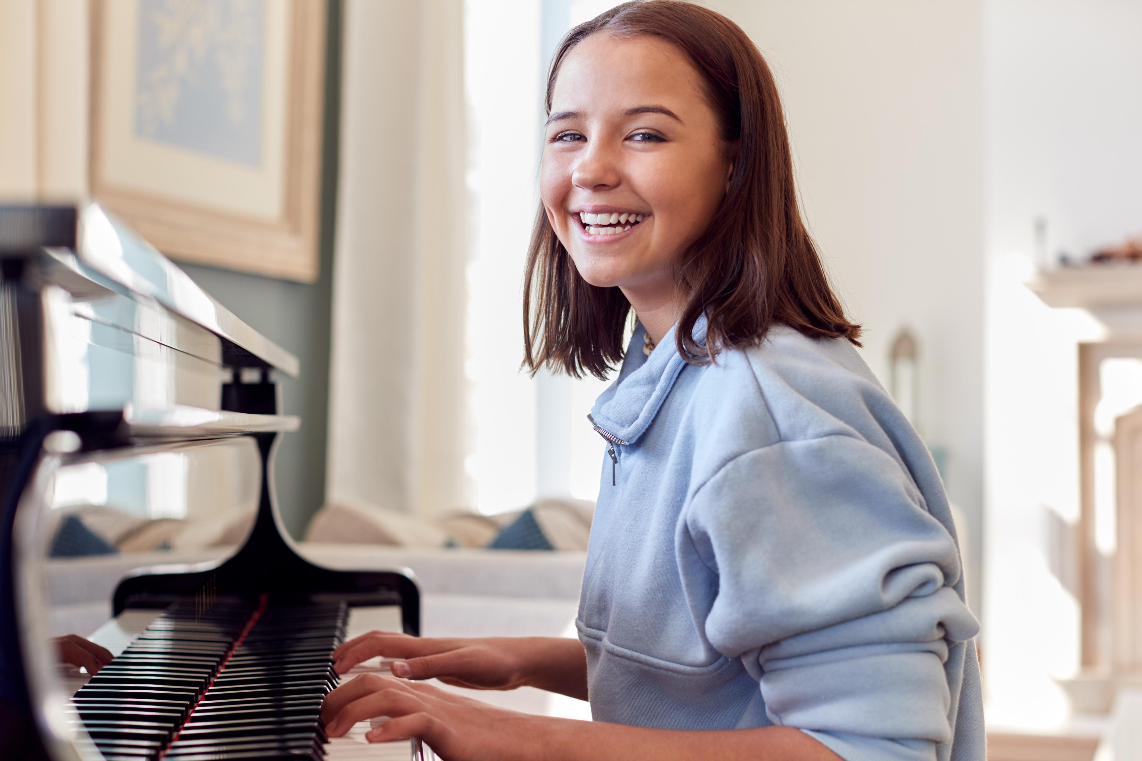 Young girl smiling while playing piano